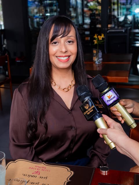 Rebeca Andrade concedendo entrevista a podcasts, com dois microfones à sua frente